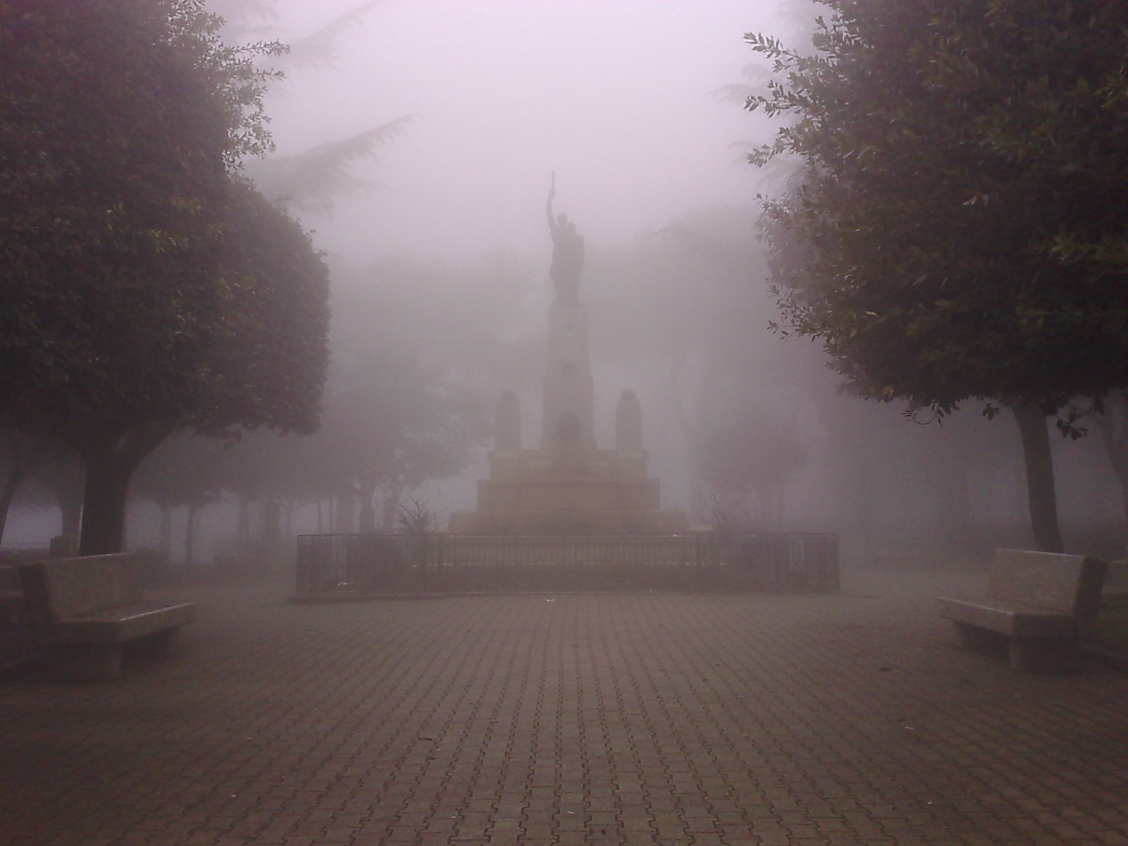 a statue sitting on top of a bench near trees