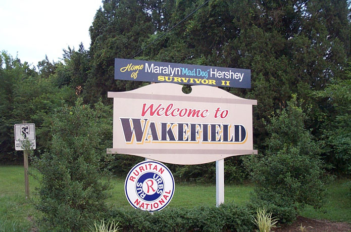 the welcome sign for a local marketplace with several signs around it