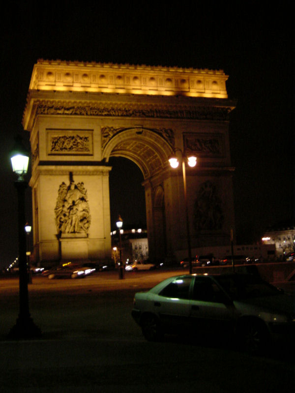 there is a green car parked near an illuminated gate