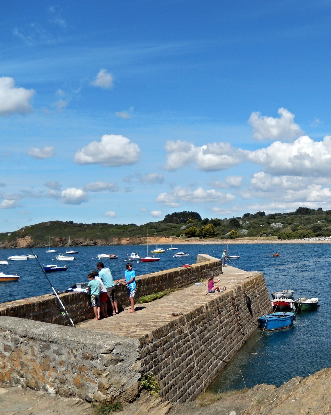 a group of people standing on a wall next to the ocean