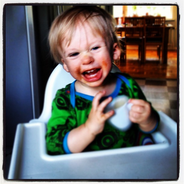 a  in a highchair with his mouth open