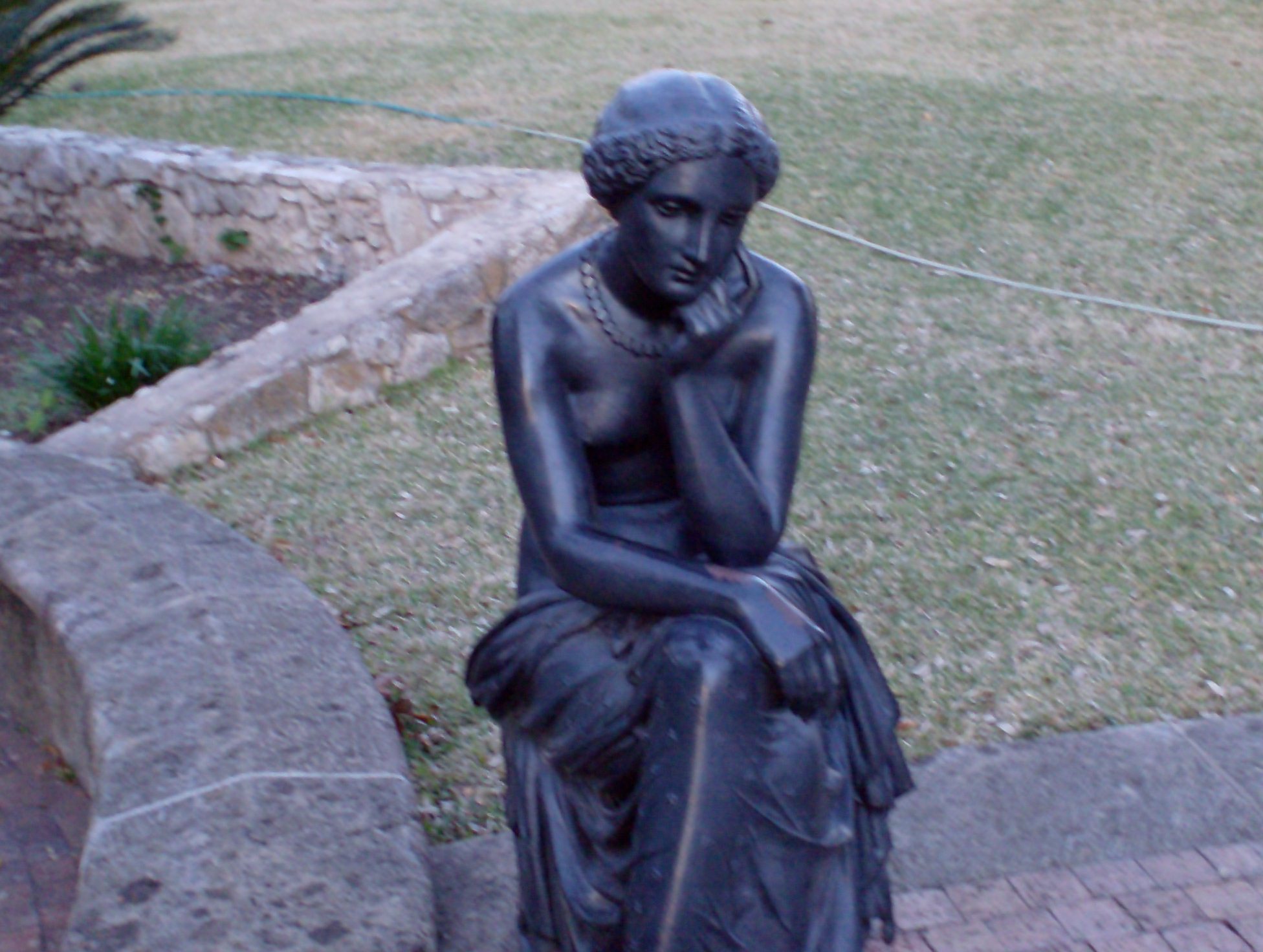 a statue sitting on top of a rock in the grass