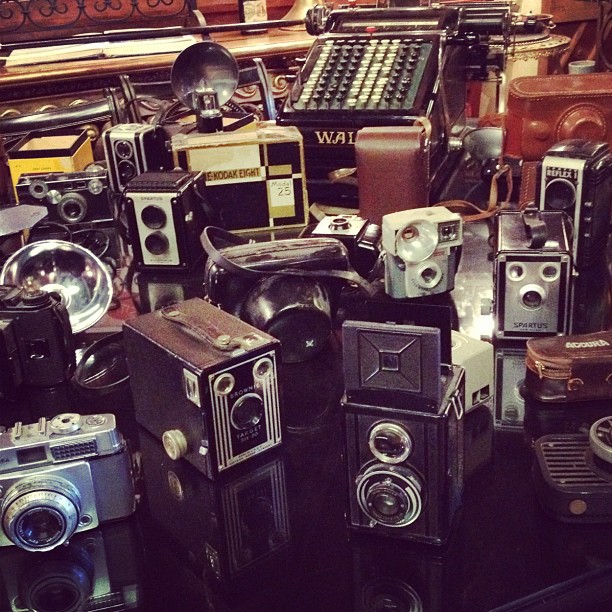 a collection of old fashioned cameras with one of the old ones on top
