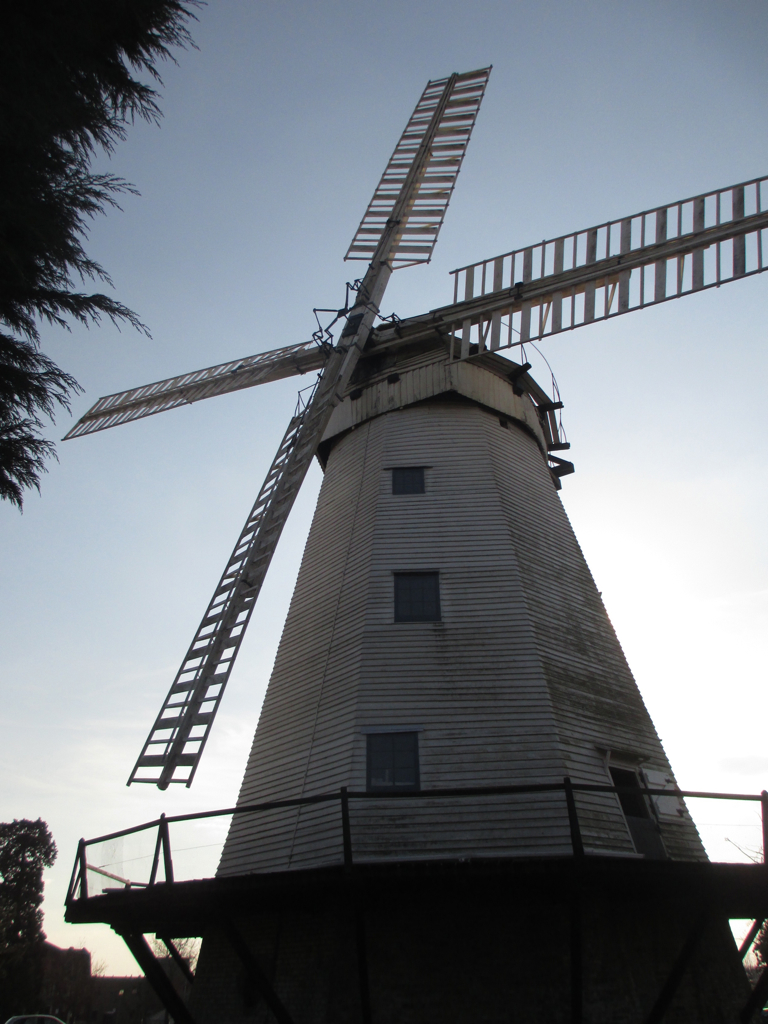 a white windmill has a long ladder on top