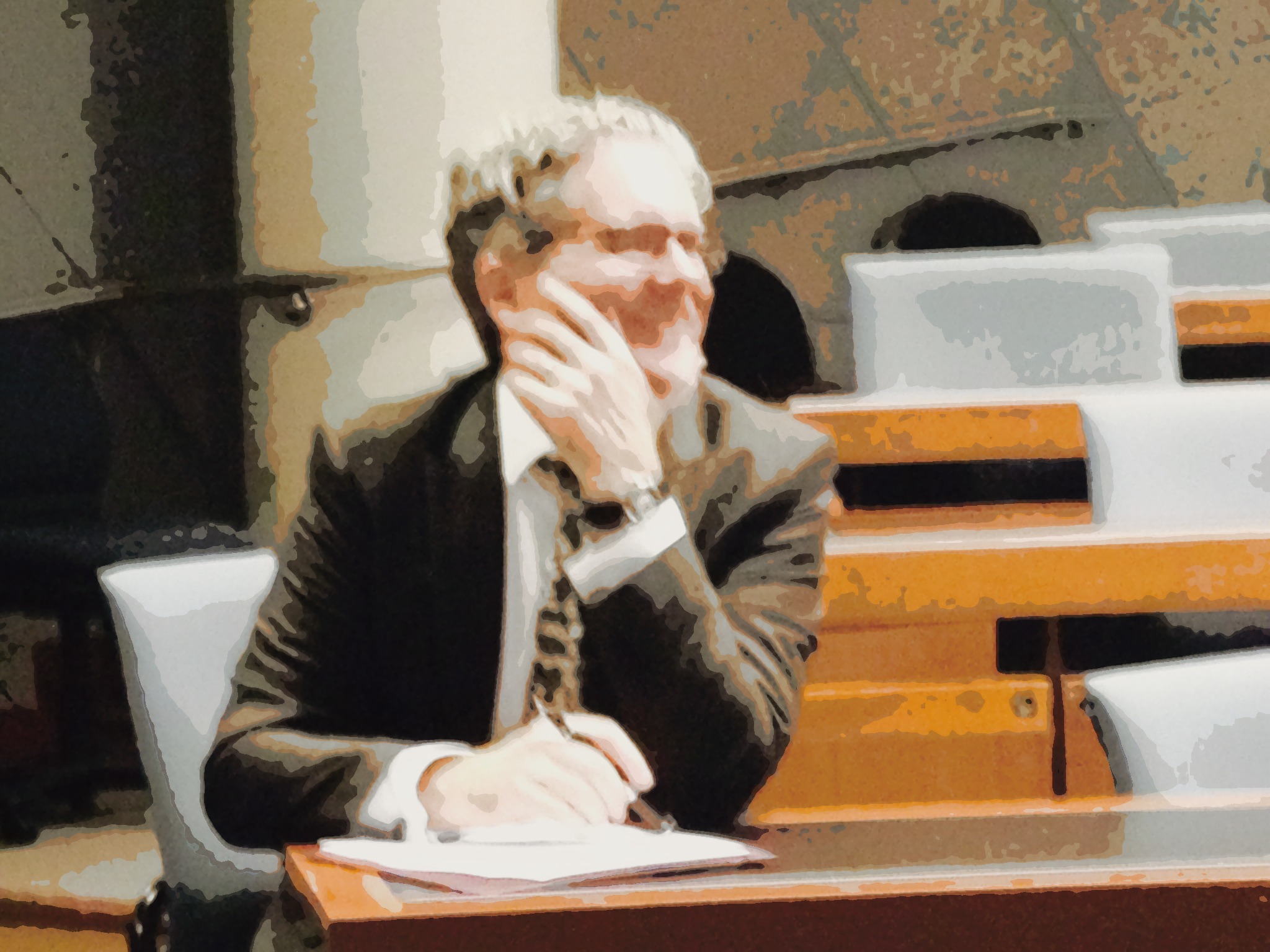 an old man in suit is talking on a phone