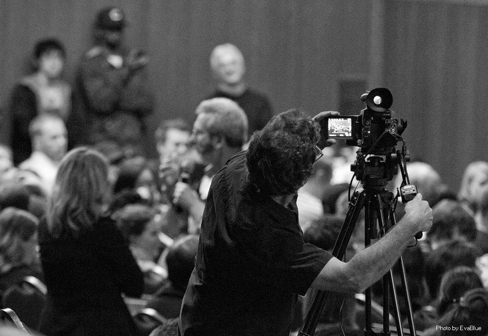 people in the audience with cameras at a meeting