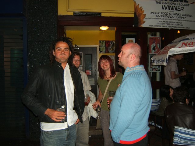 three men standing outside having drinks together