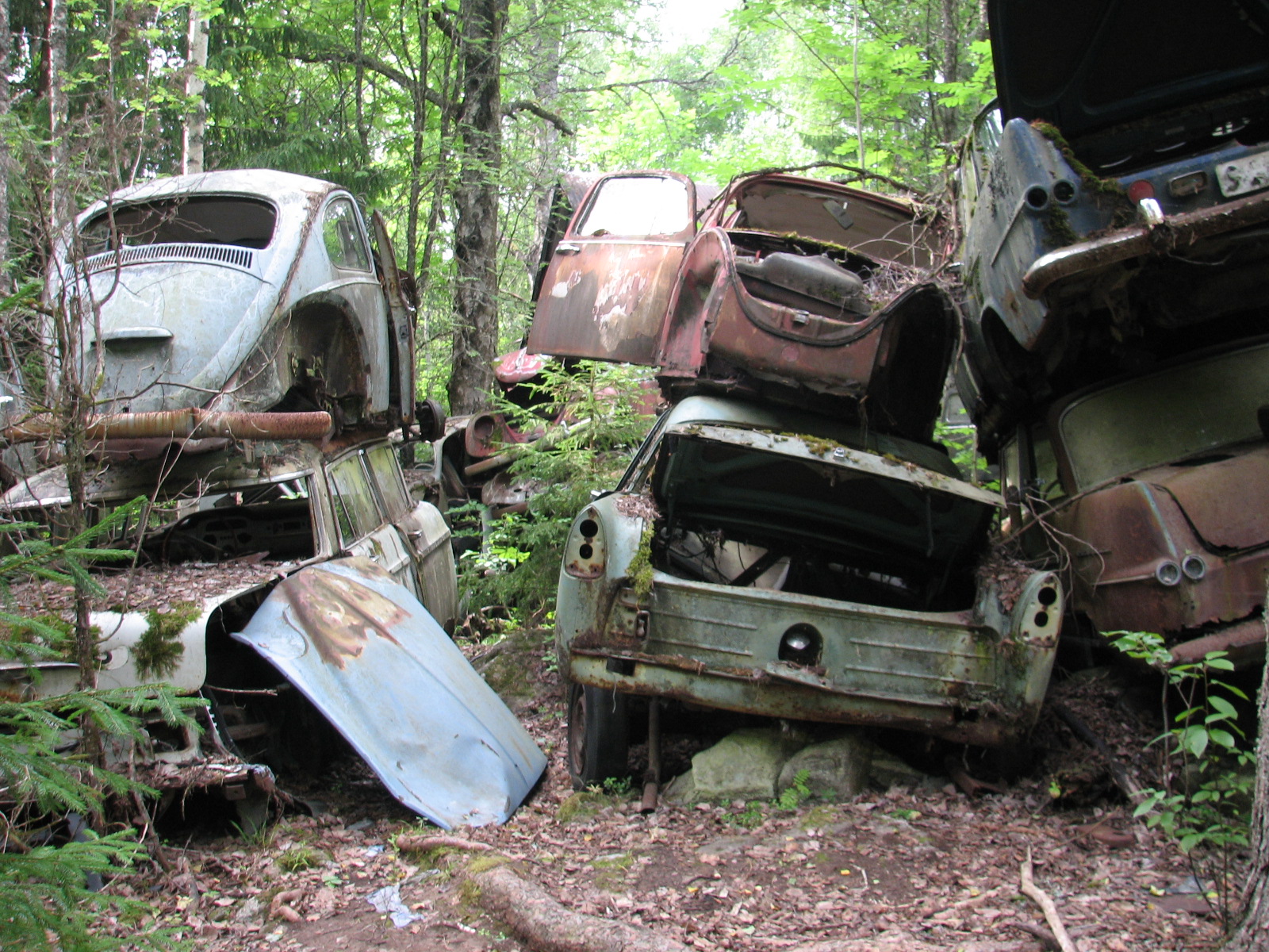 some old cars are piled into piles in the woods