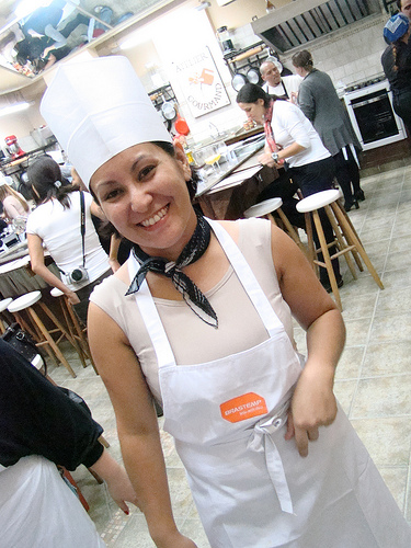 a smiling woman dressed in an apron and white hat