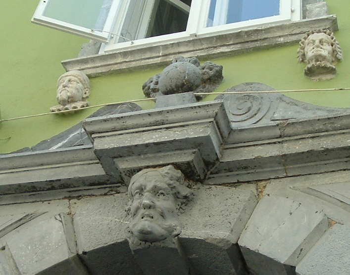 the front of a green building with stone lion heads on the corner