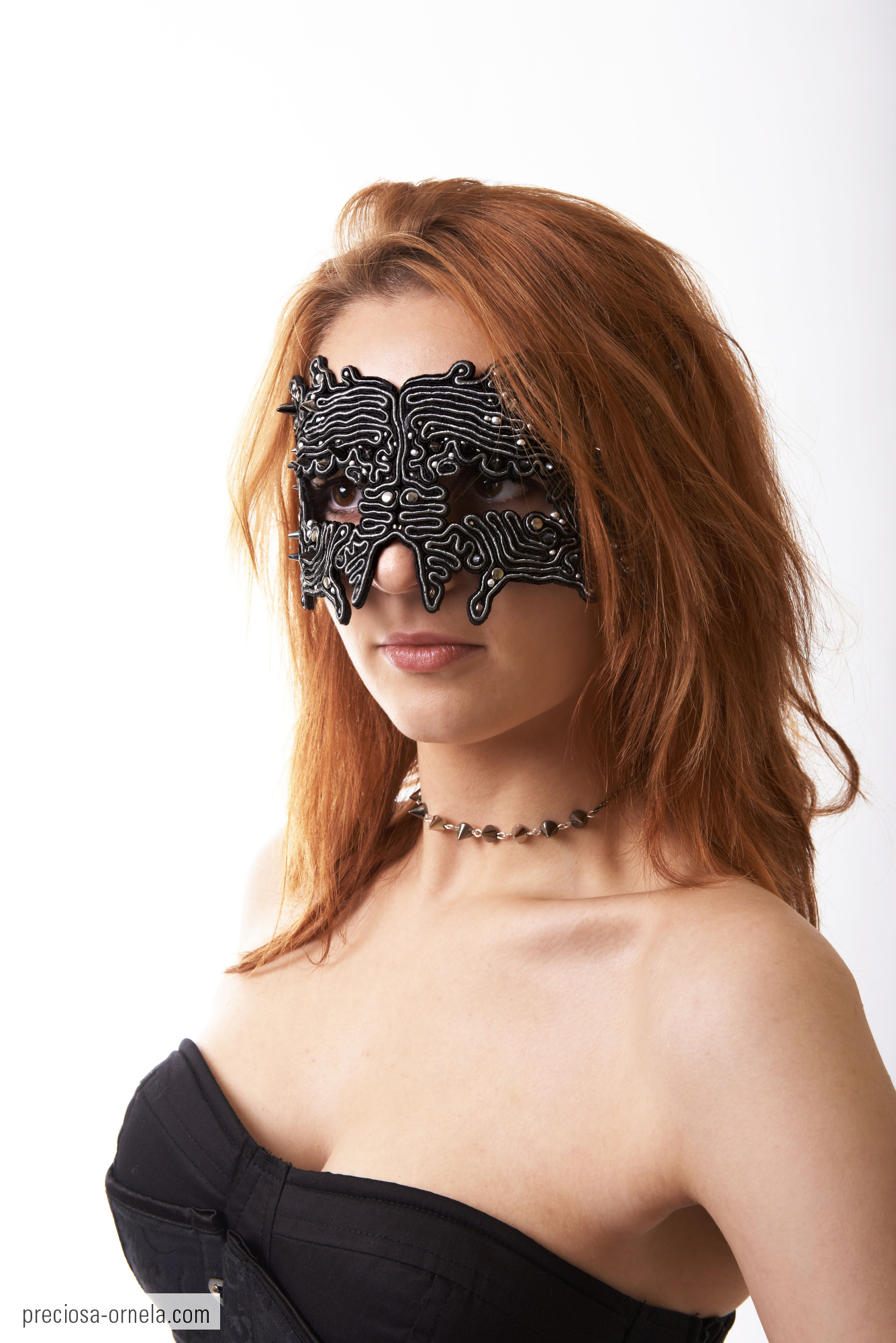 a woman wearing a black mask with jewels around her eyes