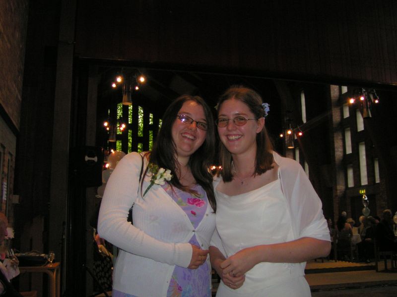 a woman in a white dress and another woman wearing a blue floral pincust on her shoulder