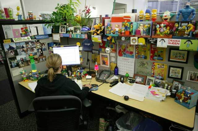 woman sitting in front of computer screen covered in knick knacks