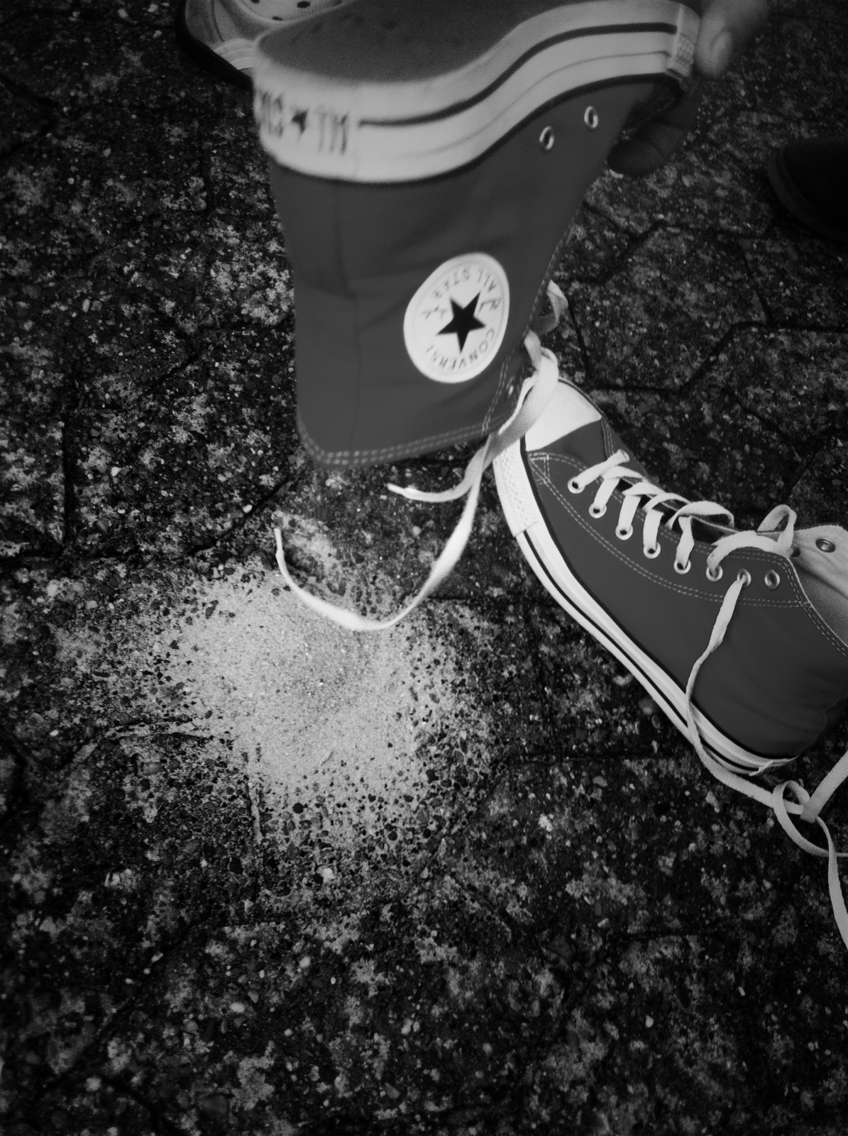 black and white pograph of the shoe of someone's converse shoes