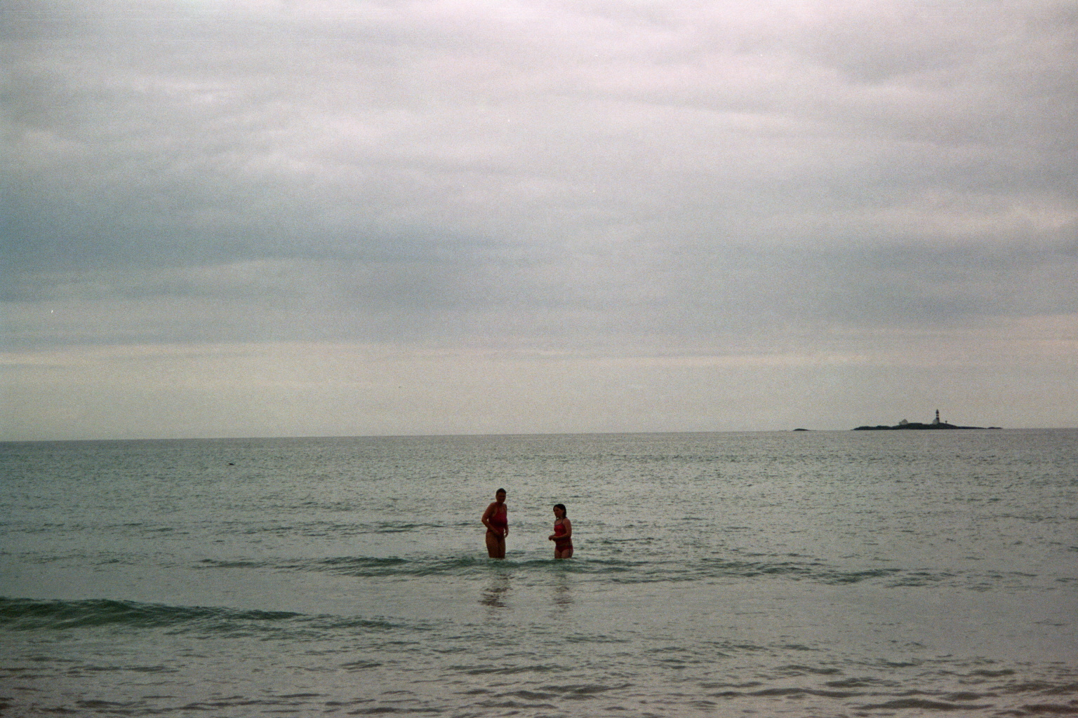 two people in the ocean on an overcast day