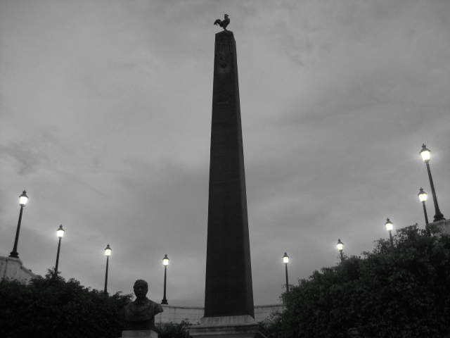a monument with lights along the side of it on a cloudy day