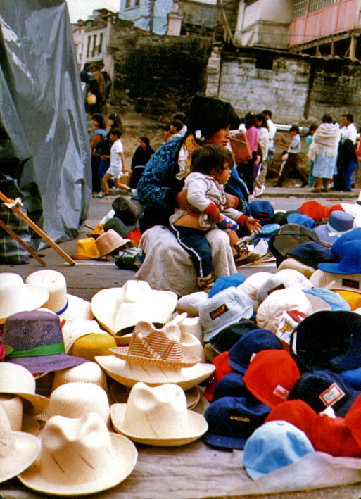 woman and child sitting among hats for sale