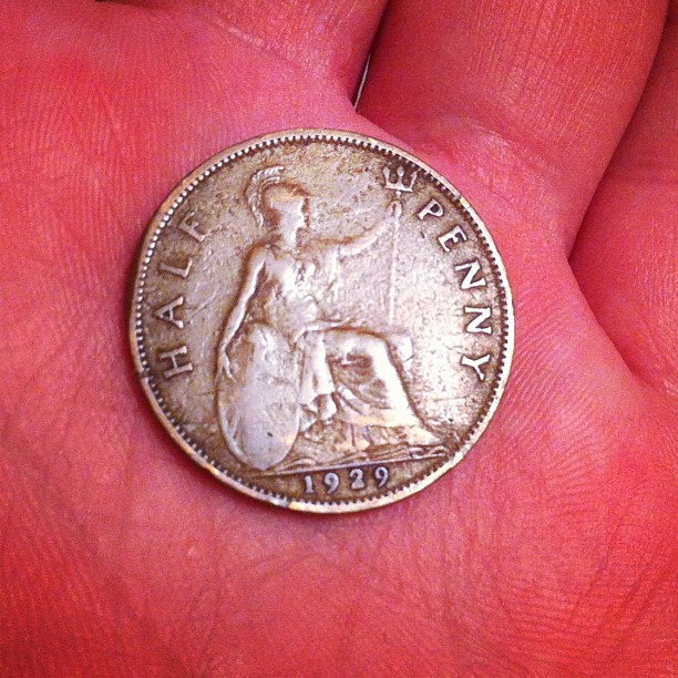 an old coin sitting on someones finger