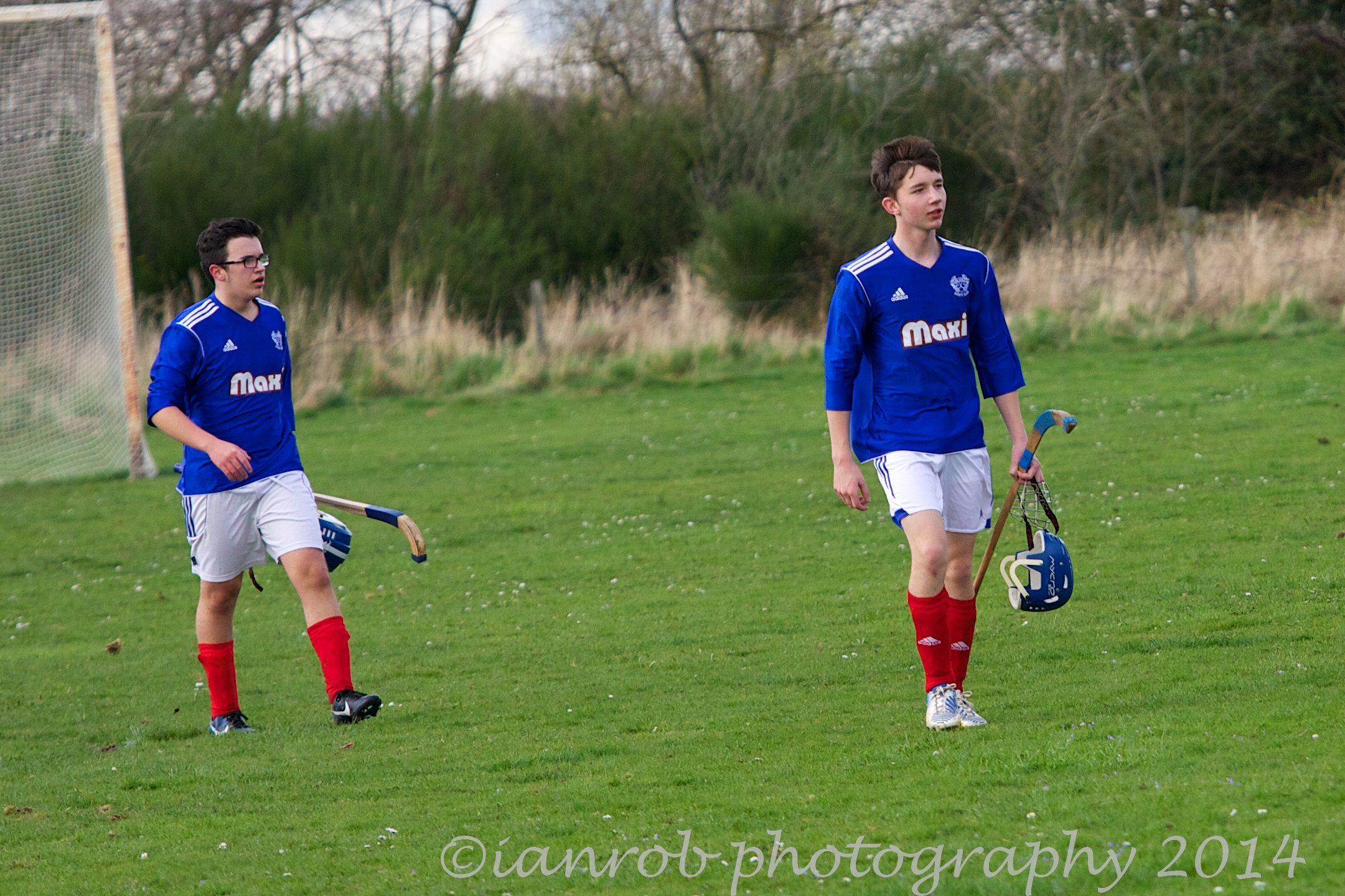 a pair of guys are playing lacrosse outside