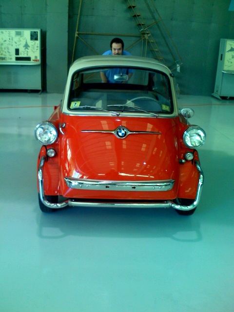 a small red car sits parked inside a building