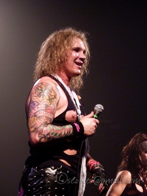 man with piercings and microphone on stage with people