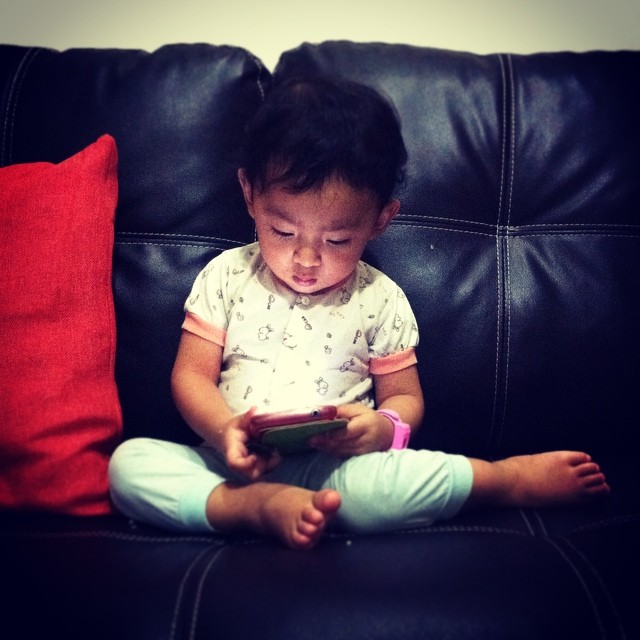 young asian girl sitting in a chair looking at a tablet