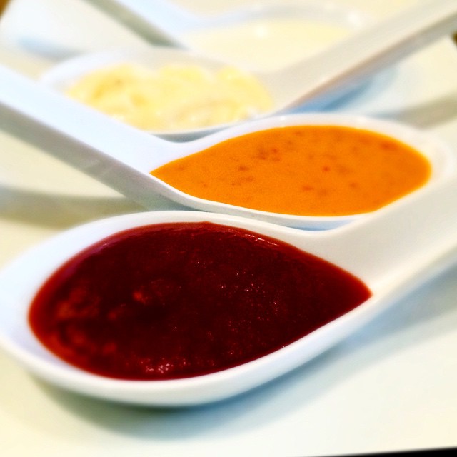 a collection of spoons containing various sauces