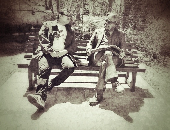 two men sit on a bench and talk