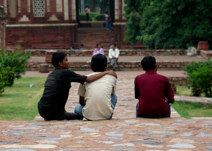 a group of young men sit on the ground in front of a building