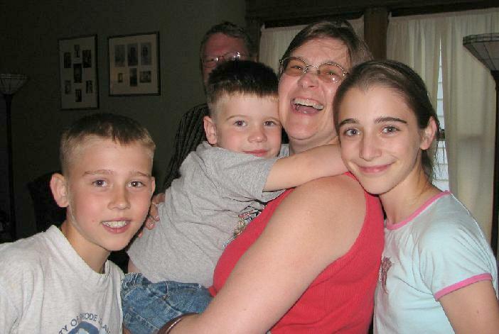 a woman standing next to two boys while they hug