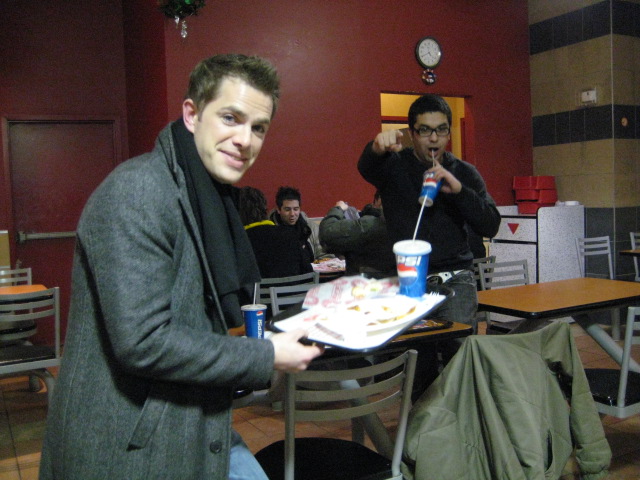 a man in a jacket is holding a plate and drinking