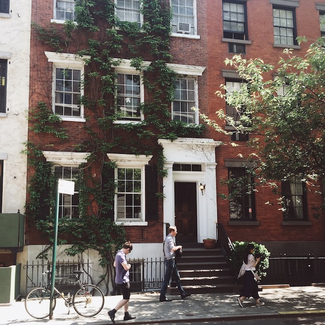 a group of people walking on a sidewalk next to an apartment building