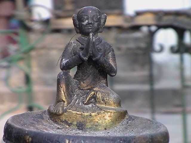 a statue that has its arms crossed holding a praying person