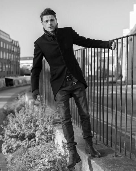 a man leaning on a railing wearing black boots