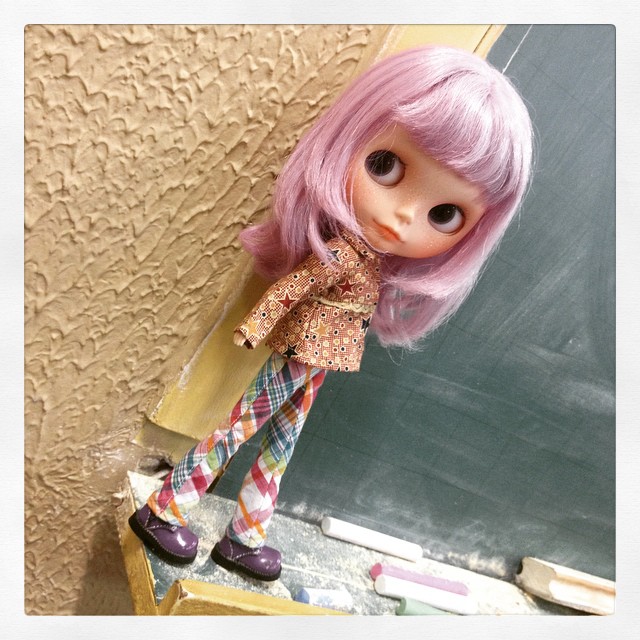 this is a doll standing next to a chalkboard