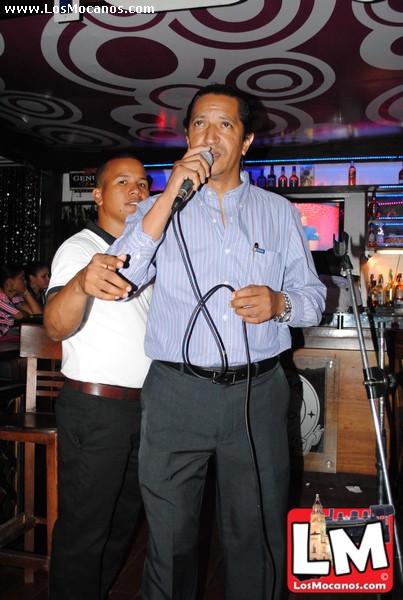 two men singing into microphones at a bar