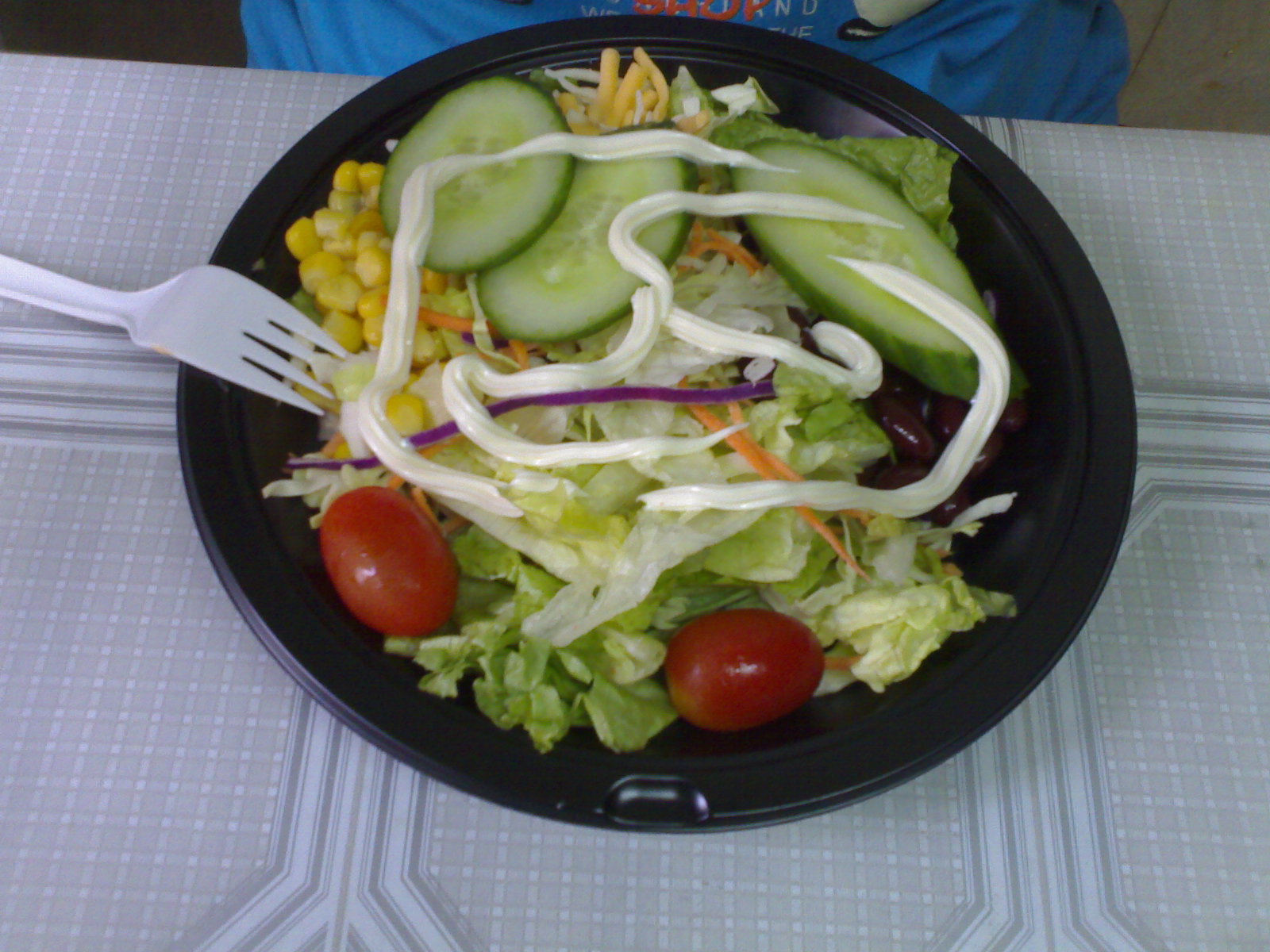 a salad sits on a black plate with a fork