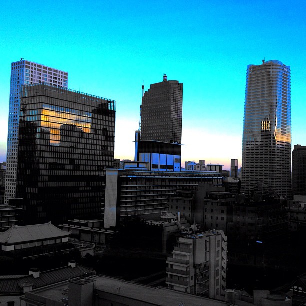 a blue sky with buildings in the background and one light lit up