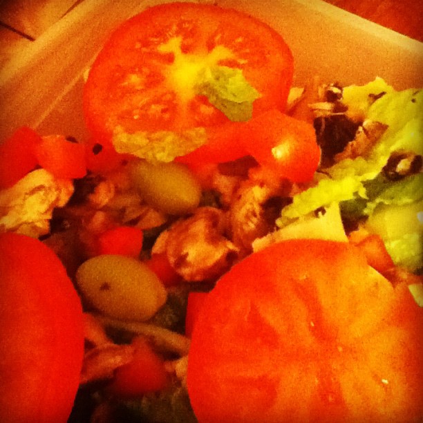 a lunch box with salad and tomatoes in it