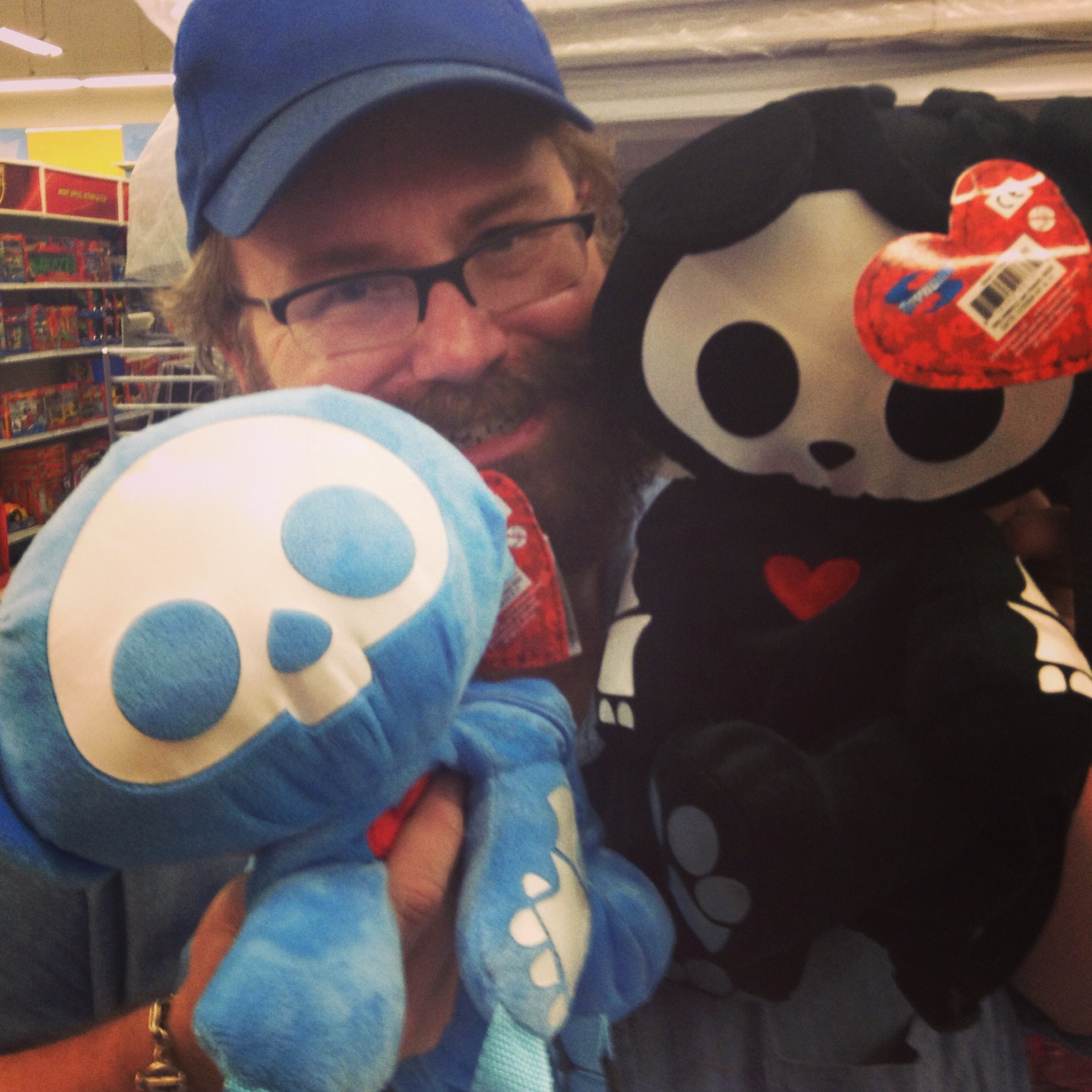 a man in glasses and hat holding onto several different types of teddy bears