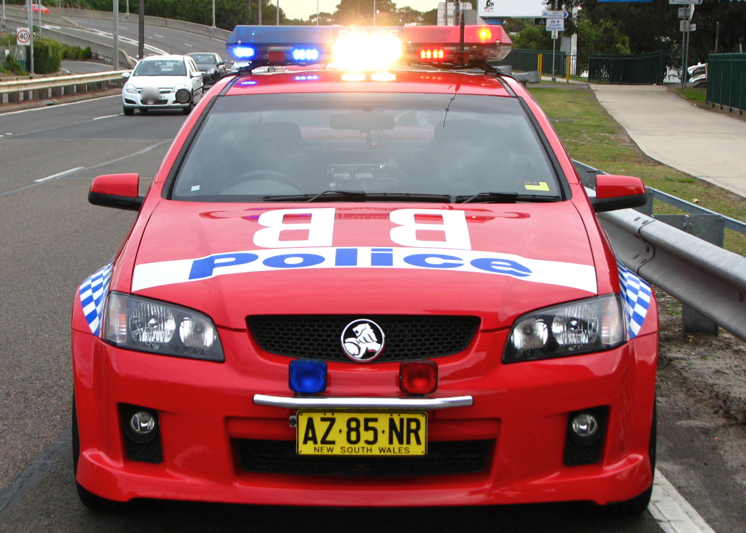 red police car with lights on, driving down the road