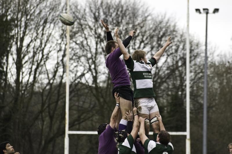 rugby players in the air on a field with their ball