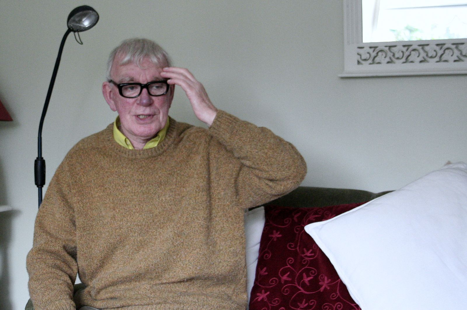 an old man sitting in a chair with his hands on the head