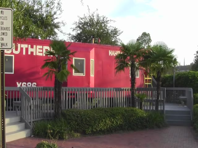 there is a building that has red paint and palm trees