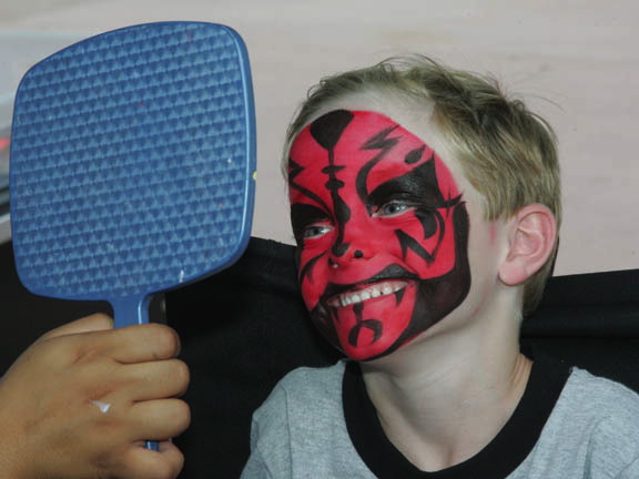 a  with his face painted red with a blue paddle