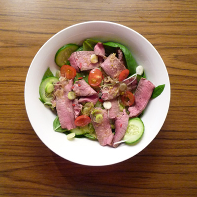 bowl with a salad of beef, cucumbers, tomatoes and red peppers