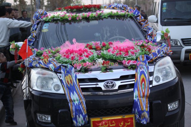 a car with a decoration on the hood, in front of a crowd