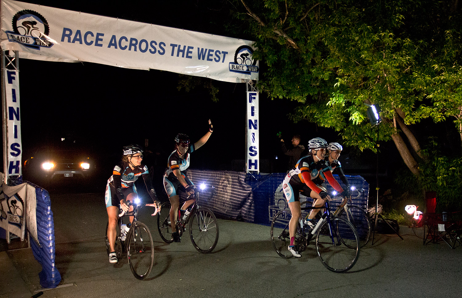 several bicyclists riding at a finish line with the lights on
