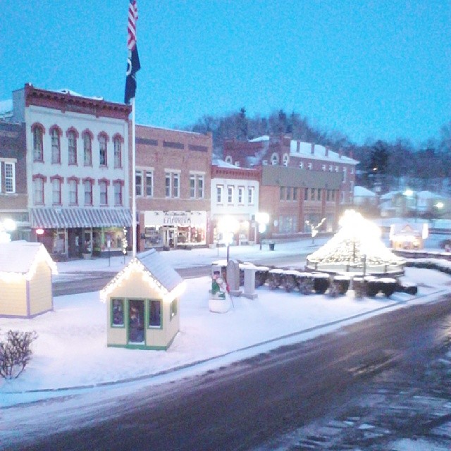 a small town covered in snow with a flag pole and buildings
