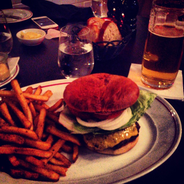 a meal on a white plate with fries, and a glass of beer